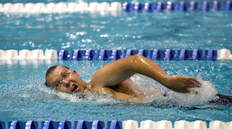 Athlet schwimmt auf Schwimmbahn. Man sieht diesen beim Kraulen.